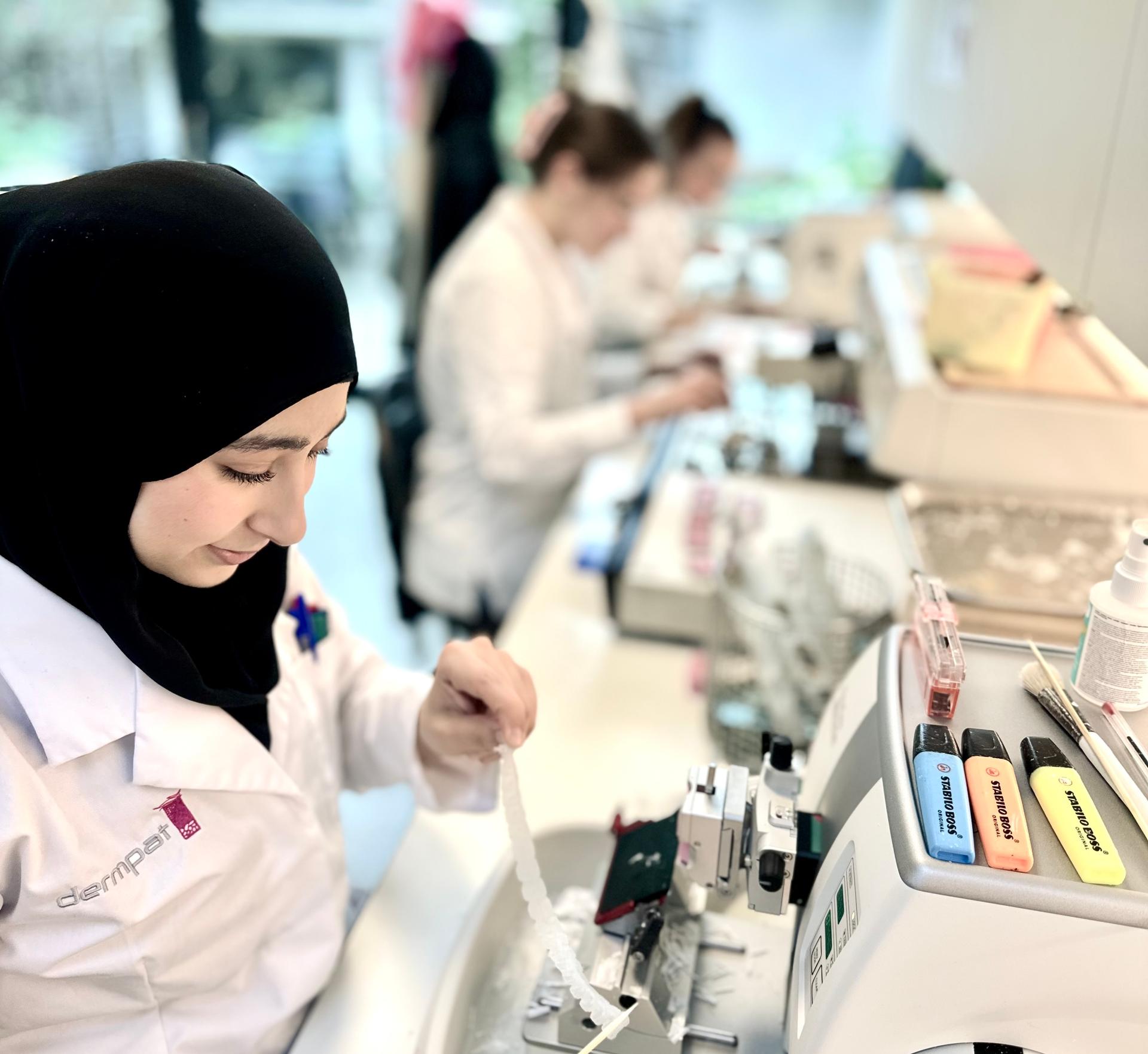 Werkende medewerker in het labo met drie aparte cellen in de onderhoek afgebeeld